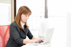 無期雇用派遣のメリット・デメリットをパソコンで調べる女性